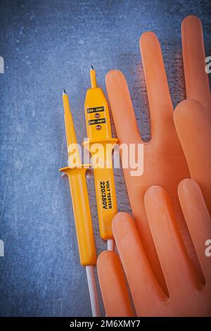 Isolierhandschuhe Elektrotester auf metallischem Hintergrund. Stockfoto