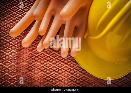 Isolierende Handschuhe Bauhelm auf dielektrischer Gummimatte. Stockfoto