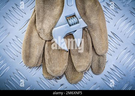 Sicherheitshandschuhe aus Leder Edelstahlaffenschlüssel auf gewelltem Metallblech Baukonzept. Stockfoto
