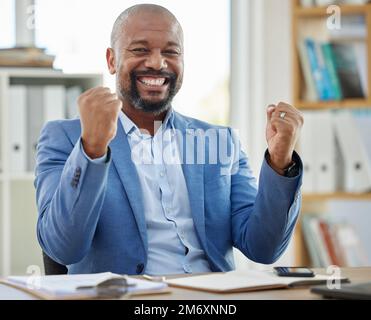 Erfolg, Gewinner und Geschäftsmann an seinem Schreibtisch im Büro für Unternehmensgewinn, Aktienmarkt oder finanzielle Aufstockung, Beförderung oder Bonus. Frohe Neuigkeiten, Faust und Stockfoto