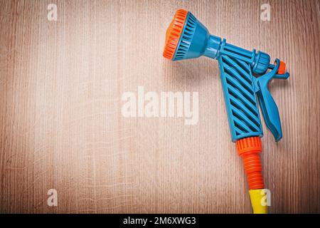 Handbesprühen von Gartengummischläuchen auf Holzbretter Gartenkonzept. Stockfoto