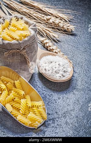 Hessische Sack-Spiralmakkaroni mit Schaufel Holzlöffel Mehl Weizen Roggenohren auf schwarzem Hintergrund. Stockfoto