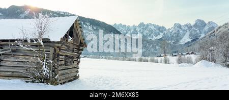 Holzhütte neben den Dachsteinbergen in Gosau mit Sonnenlicht. Stockfoto