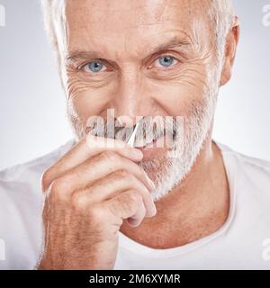 Porträt, Pinzette und Nase mit einem Senioren im Studio auf grauem Hintergrund für Körperpflege oder Körperpflege. Gesicht, Hand und Äquivalent mit einem reifen Stockfoto