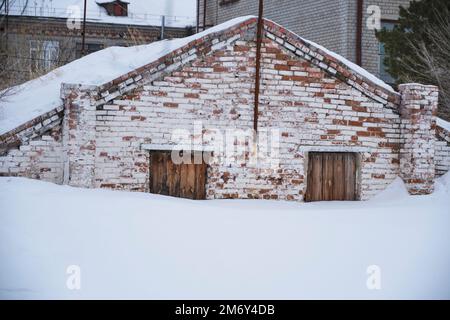 Das alte Backsteinhaus ist mit Schnee bedeckt Stockfoto