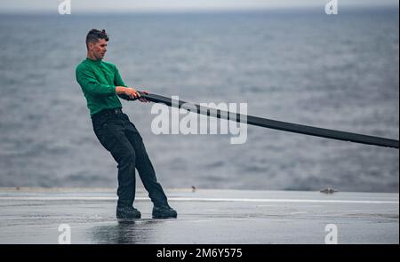 220510-N-DW158-1060 PACIFIC OCEAN (10. Mai 2022) Aviation Boatswain’s Mate (Equipment) Airman Zachary Dahl aus Pleasant Hill, Oregon, legt eine Gummiabdeckung über ein Katapult auf dem Flugdeck der USA Der einzige nach vorn eingesetzte Flugzeugträger der Navy USS Ronald Reagan (CVN 76), der während eines Tests des Abwaschsystems für Gegenmaßnahmen am Schiff eingesetzt wurde. Das Abwaschsystem für Gegenmaßnahmen wird vor, während und nach einer chemischen Kontamination verwendet, um schädliche Chemikalien oder Agenzien an der Außenseite des Schiffes zu entfernen. Ronald Reagan, das Flaggschiff der Carrier Strike Group 5, stellt eine kampfbereite Truppe bereit, die diese Prote unterstützt Stockfoto