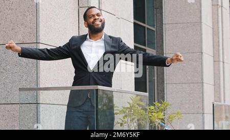 Überglücklich glücklich lustig lustig fröhlich afroamerikanischer Angestellter Unternehmer Unternehmer Unternehmer Arbeiter Mann steht auf dem Bürobalkon und tanzt entspannend Stockfoto