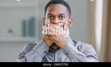 Nahaufnahme afroamerikanischer bärtiger ethnischer männlicher Millennials-Geschäftsmann Manager Manager-Manager, der mit Händen vor die Kamera schaut, verdeckt den Mund mit Bedauern Stockfoto