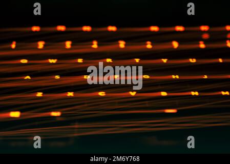 Leicht gemalte Buchstaben und Zahlen auf der Tastatur. Wunderschöner, farbenfroher Hintergrund. Lichtermalerei mit langer Belichtung, rote gekrümmte Linien in leuchtendem Neon. Stockfoto