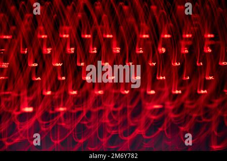 Leicht gemalte Buchstaben und Zahlen auf der Tastatur. Wunderschöner, farbenfroher Hintergrund. Lichtermalerei mit langer Belichtung, rote gekrümmte Linien in leuchtendem Neon. Stockfoto