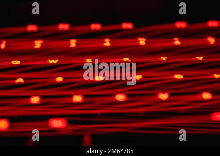 Leicht gemalte Buchstaben und Zahlen auf der Tastatur. Wunderschöner, farbenfroher Hintergrund. Lichtermalerei mit langer Belichtung, rote gekrümmte Linien in leuchtendem Neon. Stockfoto