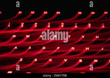 Helle Malerei auf Tastaturbuchstaben. Wunderschöner, farbenfroher Hintergrund. Lichtermalerei mit langer Belichtung. Rote gekrümmte Linien in leuchtendem Neon auf schwarzem Hintergrund. Stockfoto