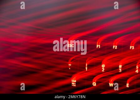 Helle Malerei auf Tastaturbuchstaben. Wunderschöner, farbenfroher Hintergrund. Lichtermalerei mit langer Belichtung. Rote gekrümmte Linien in leuchtendem Neon auf schwarzem Hintergrund. Stockfoto