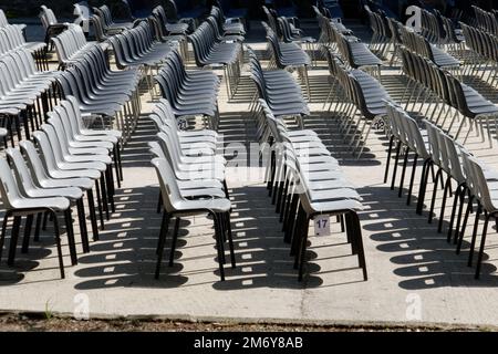 Viele schwarze und weiße Plastikstühle wurden mit Reihe und Säule für Freiluftkonzerte oder Open-Air-Veranstaltungen aufgestellt . Freie Plätze Stockfoto