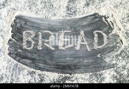 Mehl auf dunklem Hintergrund und Text für BROTTEIG. Backwaren-Hintergrundkonzept Stockfoto