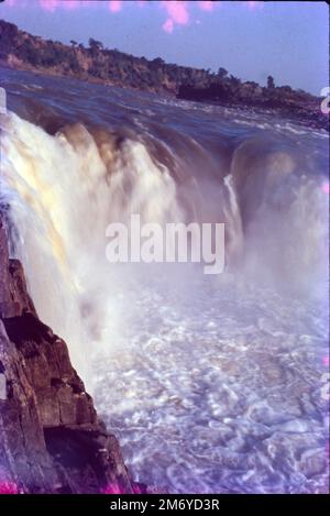 Die Dhuandhar-Fälle (धुआंधार) sind ein Wasserfall im Bezirk Jabalpur im indischen Bundesstaat Madhya Pradesh. Dhuandhar-Wasserfälle in Bhedaghat. Der Fluss Narmada, der sich durch die weltberühmten Marmorfelsen zieht, verengt sich und stürzt dann in einen Wasserfall, der als Dhuandhar bekannt ist. Stockfoto