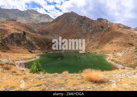 Das Smaragdwasser des Loie-Sees (Lago di Loie) ist umgeben von Granitfelsen mit im Herbst verwelktem gelbem Gras im Parco Nazionale Gran Paradiso Stockfoto