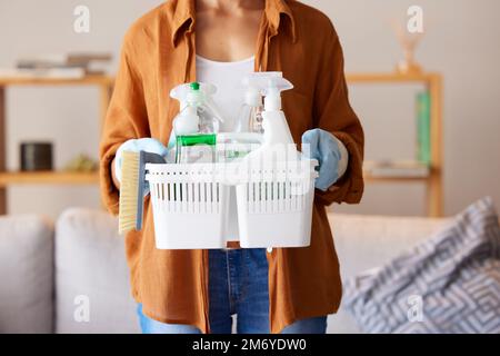 Reinigung, Hygiene und Waschmittel mit einer Frau, die einen Korb mit Produkten als Reinigungsmittel in einem Haus hält. Bakterien, Behälter- und Sprühflasche mit einer Frau Stockfoto