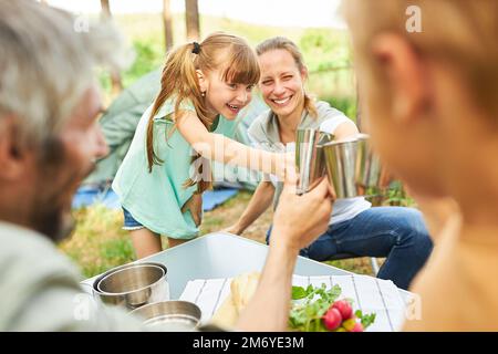 Fröhliche Familie, die während der Sommerferien auf dem Campingplatz frühstückt und Tassen toastet Stockfoto