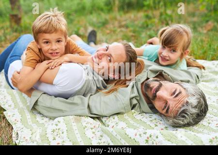 Porträt einer lächelnden Familie, die während der Sommerferien auf einer Decke auf dem Campingplatz liegt Stockfoto