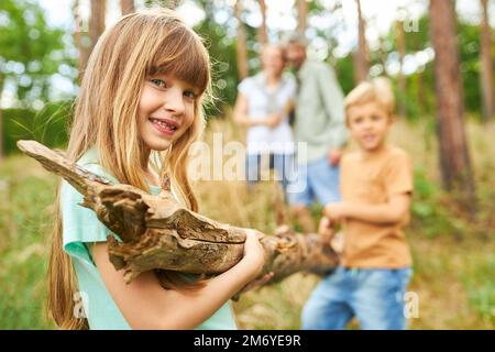 Porträt eines glücklichen Mädchens, das mit seinem Bruder Holz sammelte, während er mit seiner Familie im Wald zeltete Stockfoto