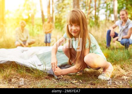 Mädchen, die im Sommer ein Zelt aufstellen, während sie mit Eltern und Bruder campen Stockfoto