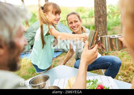 Glückliche Familie, die während der Sommerferien auf dem Campingplatz Tassen toastet Stockfoto