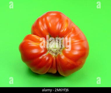 Tomate auf grünem Hintergrund isoliert. Mit Beschneidungspfad. Volle Schärfentiefe. Stockfoto