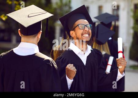 Glücklicher, aufgeregter Universitätsabschluss feiert und amüsiert sich bei seiner Abschlusszeremonie Stockfoto