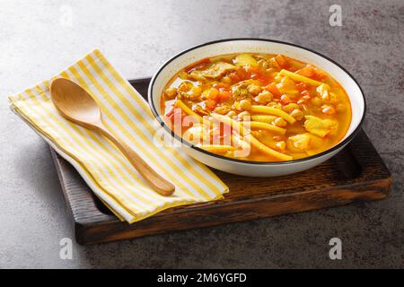 Gemüsesuppe mit Fleisch, Pasta und Kichererbsen in Nahaufnahme auf einem Teller auf dem Tisch. Horizontal Stockfoto
