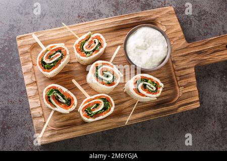 Leckere Brötchen mit Lachs, Käse und Gemüse für einen Brunch auf dem Brett auf dem Tisch. Horizontale Draufsicht von oben Stockfoto