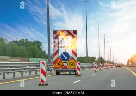 Straßenfahrzeuge mit Anhänger und Geschwindigkeitsbegrenzung und Warnschildern zur Spurwarnung, ein heller Pfeil zeigt eine geschlossene Spur an Stockfoto