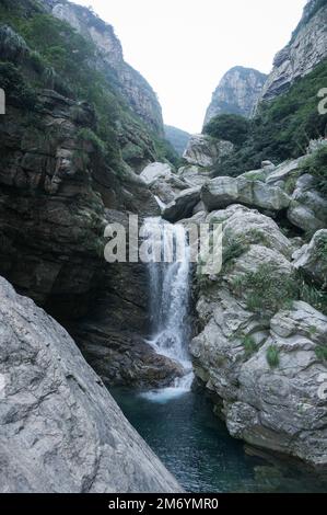 Eine vertikale Aufnahme eines Wasserfalls, der die Felsen hinunterfällt. Stockfoto