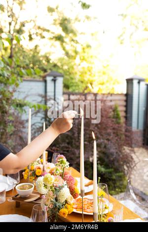 Hochzeit. Bankett. Stühle und ein Tisch für Gäste, dekoriert mit Kerzen, werden mit Besteck und Geschirr serviert und mit gelber Tischdecke bedeckt. Die Stockfoto