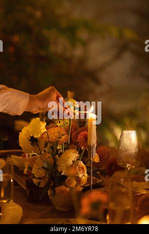 Hochzeit. Bankett. Stühle und ein Tisch für Gäste, dekoriert mit Kerzen, werden mit Besteck und Geschirr serviert und mit gelber Tischdecke bedeckt. Die Stockfoto