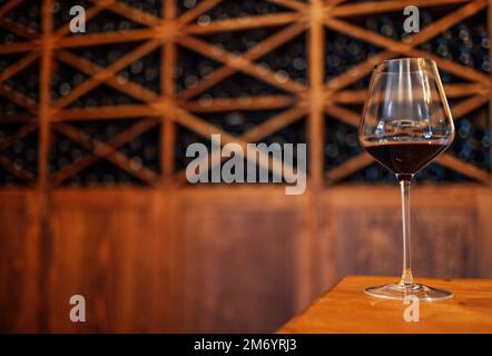 Verkostung. Weinflaschen auf einem Holzregal. Weinbar. Glasur mit Rotwein auf Holzhintergrund Stockfoto