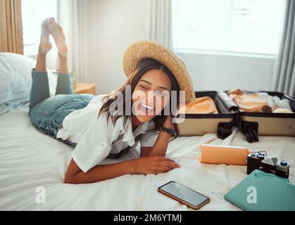 Glücklich, Reisetasche und Frau auf einem Hotelbett mit Koffer bereit für den Sommerurlaub. Gepäck, Schlafzimmer und Lächeln einer Person entspannen Sie sich in der Unterkunft Stockfoto