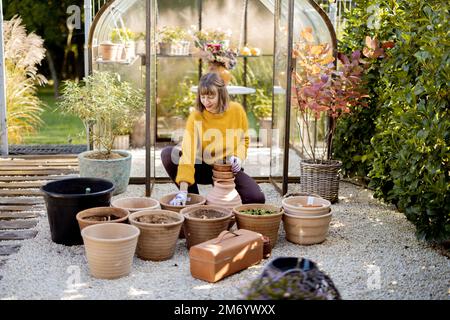 Frau pflanzt Blumen in Krügen im Garten Stockfoto