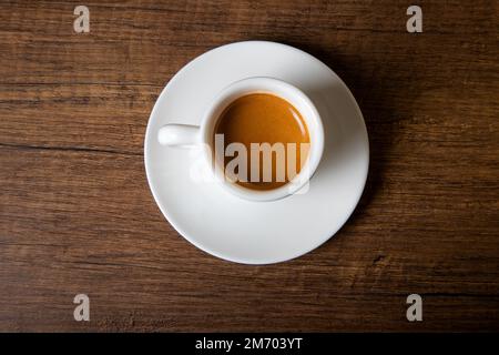 Weiße Tasse Espresso auf einem Holztisch, Draufsicht Stockfoto