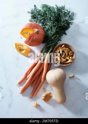 Draufsicht mit herbstfarbenen Produkten. Karotten, Kürbis, Butternusskürbis Stockfoto