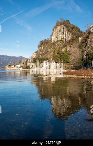 Castelveccana, Italien- 12-27-2022: Alte zerstörte Öfen mit Schornsteinen mit roten Ziegelsteinen, die auf dem Wasser des Lago Maggiore im Parco delle Fornac reflektieren Stockfoto