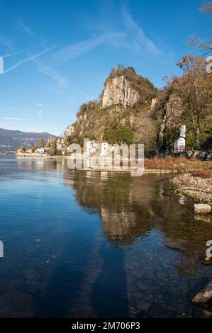 Castelveccana, Italien- 12-27-2022: Alte zerstörte Öfen mit Schornsteinen mit roten Ziegelsteinen, die auf dem Wasser des Lago Maggiore im Parco delle Fornac reflektieren Stockfoto