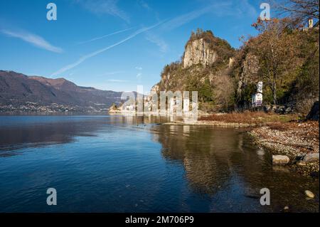 Castelveccana, Italien- 12-27-2022: Alte zerstörte Öfen mit Schornsteinen mit roten Ziegelsteinen, die auf dem Wasser des Lago Maggiore im Parco delle Fornac reflektieren Stockfoto