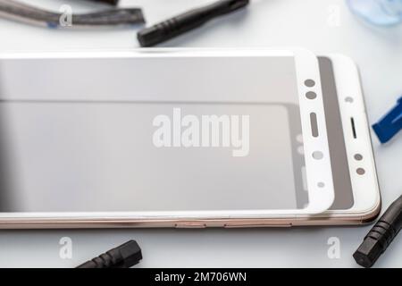 Wartung und Reparatur von Smartphones. Viele Schutzfolien aus gehärtetem Glas und Mobiltelefone ersetzen das Konzept Stockfoto