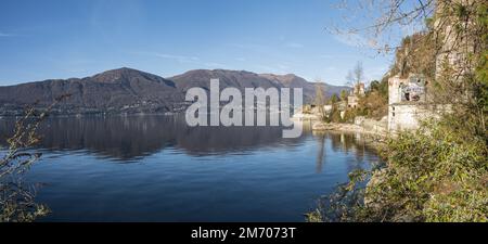 Castelveccana, Italien- 12-27-2022: Extra Weitwinkelblick auf den Lago Maggiore mit den Bergen und Öfen von Caldè, die sich im Wasser spiegeln Stockfoto