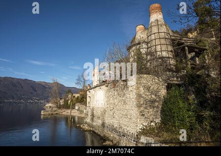 Castelveccana, Italien- 12-27-2022: Rote Ziegelschornsteine und verlassene Öfen mit Vegetation bedeckt in Caldè am Lago Maggiore Stockfoto