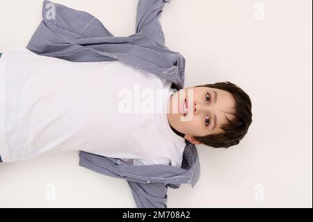 Ein multiethnischer, bezaubernder Teenager mit weißem T-Shirt und blauem Hemd, der in die Kamera schaut, isoliert auf weißem Hintergrund Stockfoto