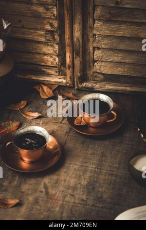 Frischer schwarzer Kaffee, serviert in einer Kupfertasse und Untertasse Stockfoto