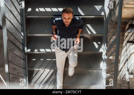 Ein Typ in Hemd und Hose posiert und läuft durch die Stadt Stockfoto