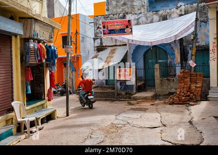 Pushkar, Indien - 7. November 2019: Männer auf einem Motorrad in der Nähe eines Bekleidungsgeschäfts in der Straße von Pushkar, Rajasthan, Indien Stockfoto